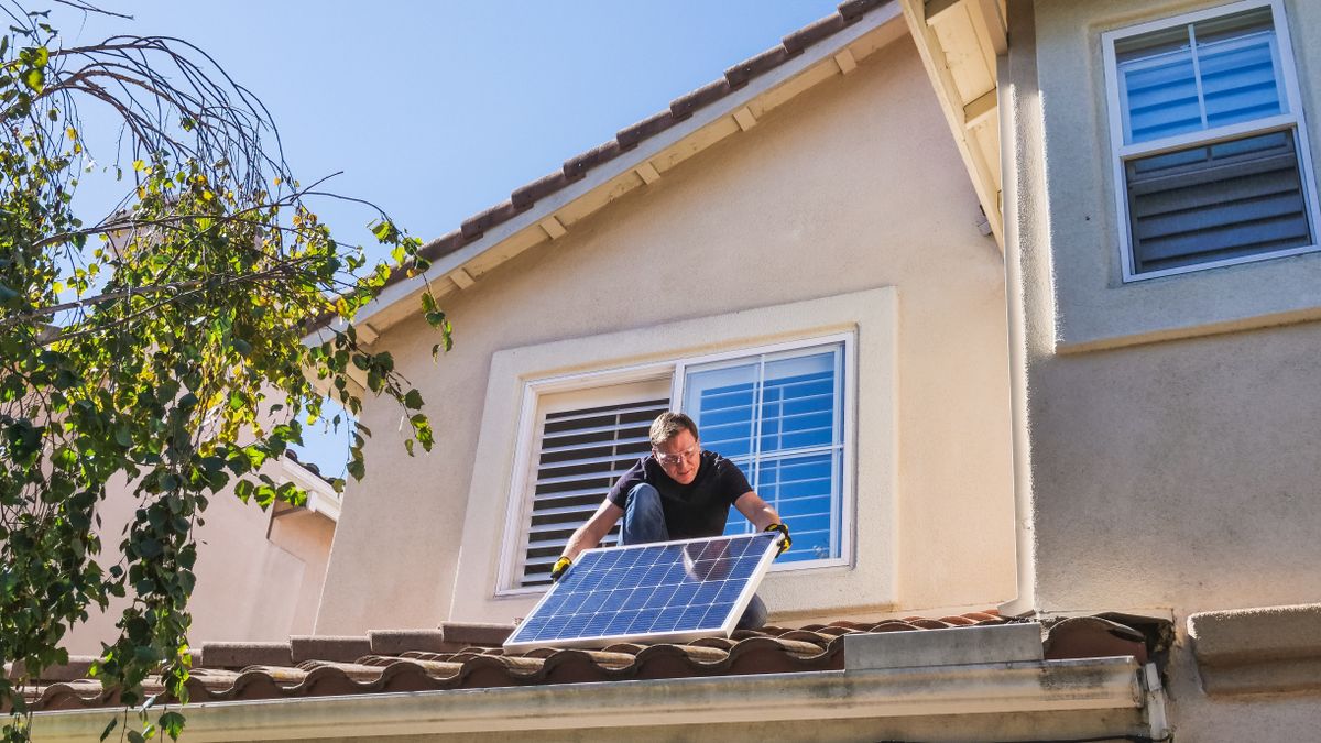 A person inspecting a photovoltaic panel on a roof