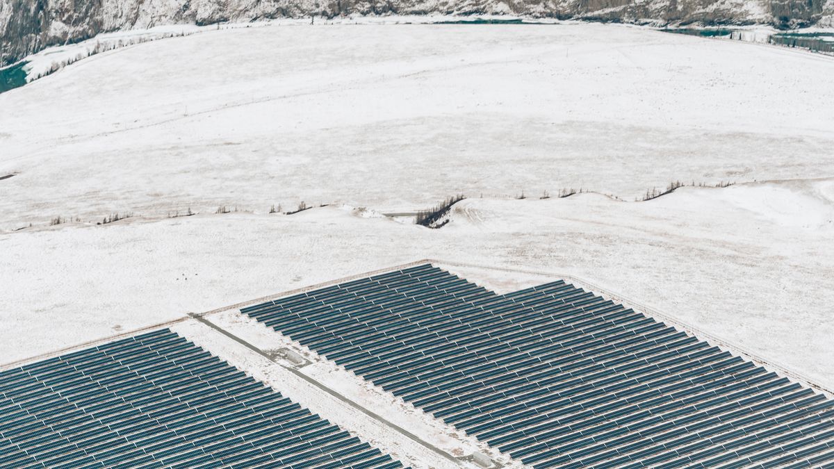 Aerial view of a solar power plant on a snow-covered field during winter